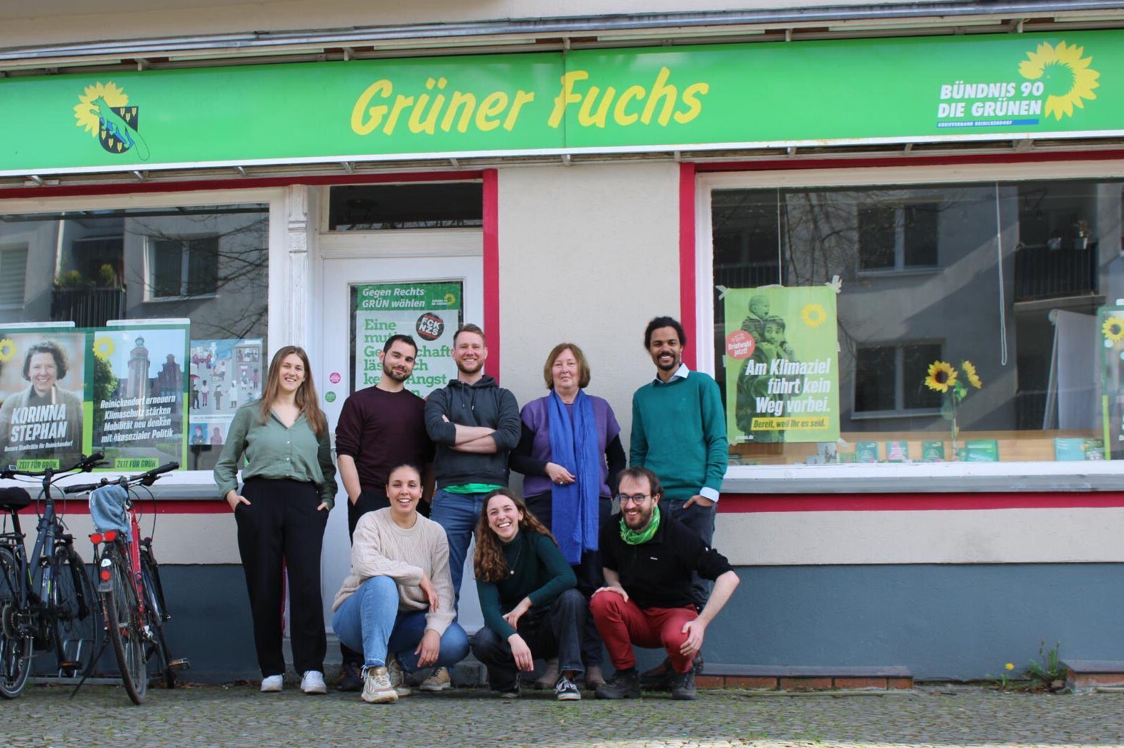 Das Bidl zeigt ein Gruppenfoto des Vorstands vom Kreisverband Reinickendorf. Die Mitglieder des Vorstands posieren dabei vor der Geschäftsstelle des Kreisverbands in der Brunowstraße. Über dem Eingang ist der Schriftzug "Grüner Fuchs" zu sehen. 