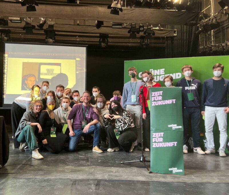 Das Bild zeigt ein Gruppenfoto von einem Treffen der Grünen Jugend Nordberlin. Im Vordergrund sieht man den SLogan: Zeit für Zukunft. 